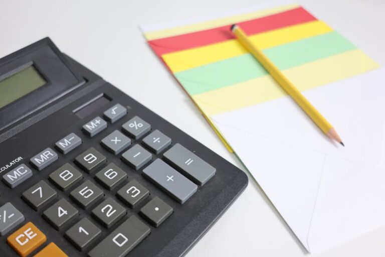 Calculator and notepad with pencil on white surface