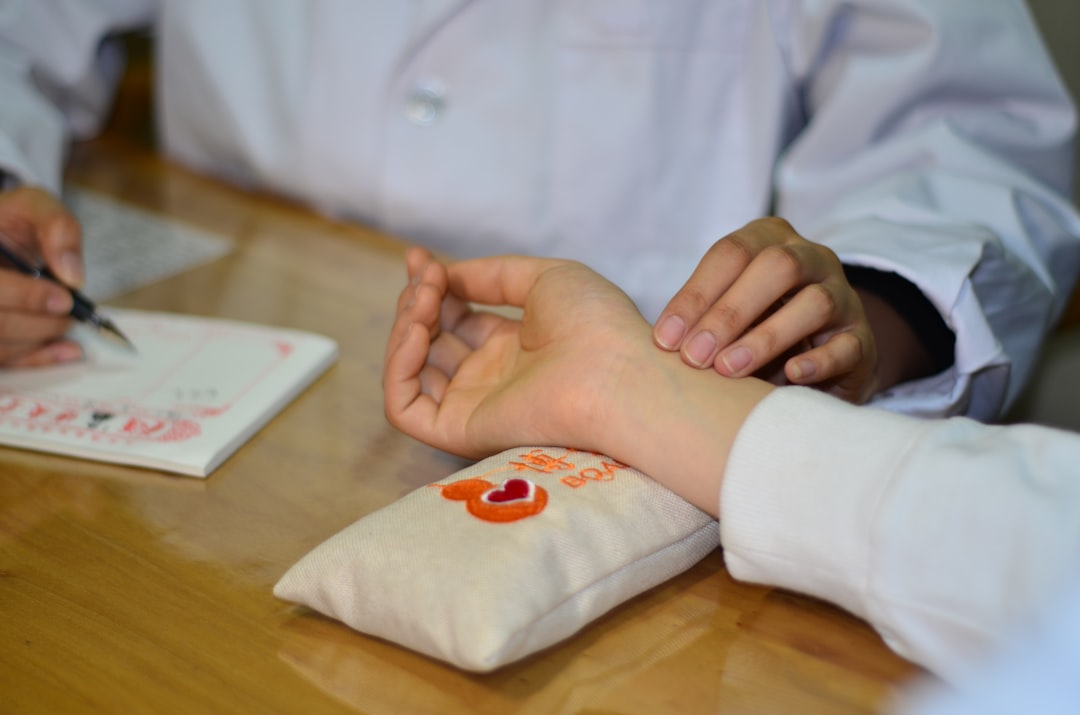 person in white long sleeve shirt with red and white heart tattoo on right hand