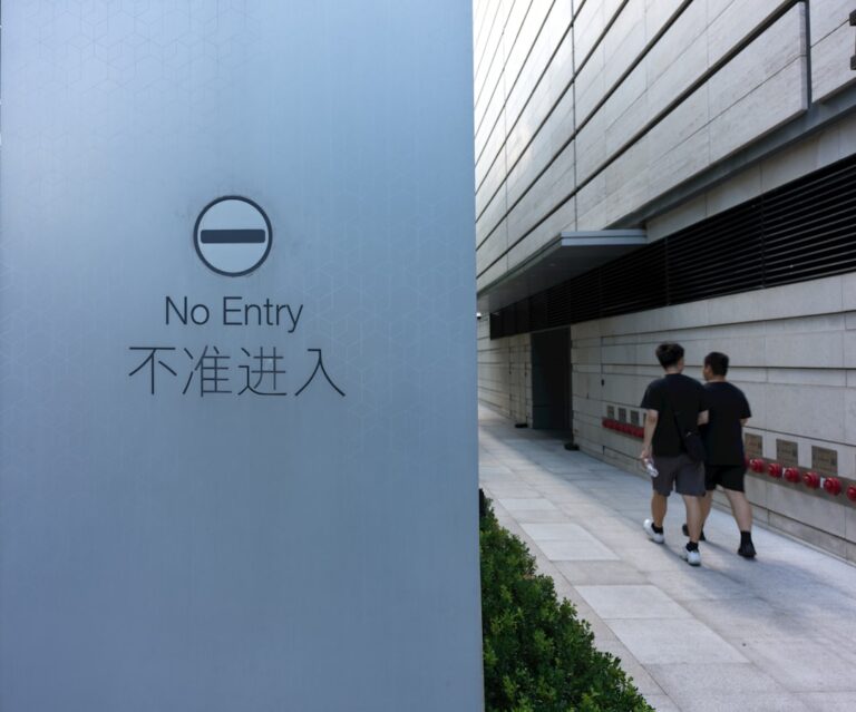 Two people walking down a sidewalk next to a building