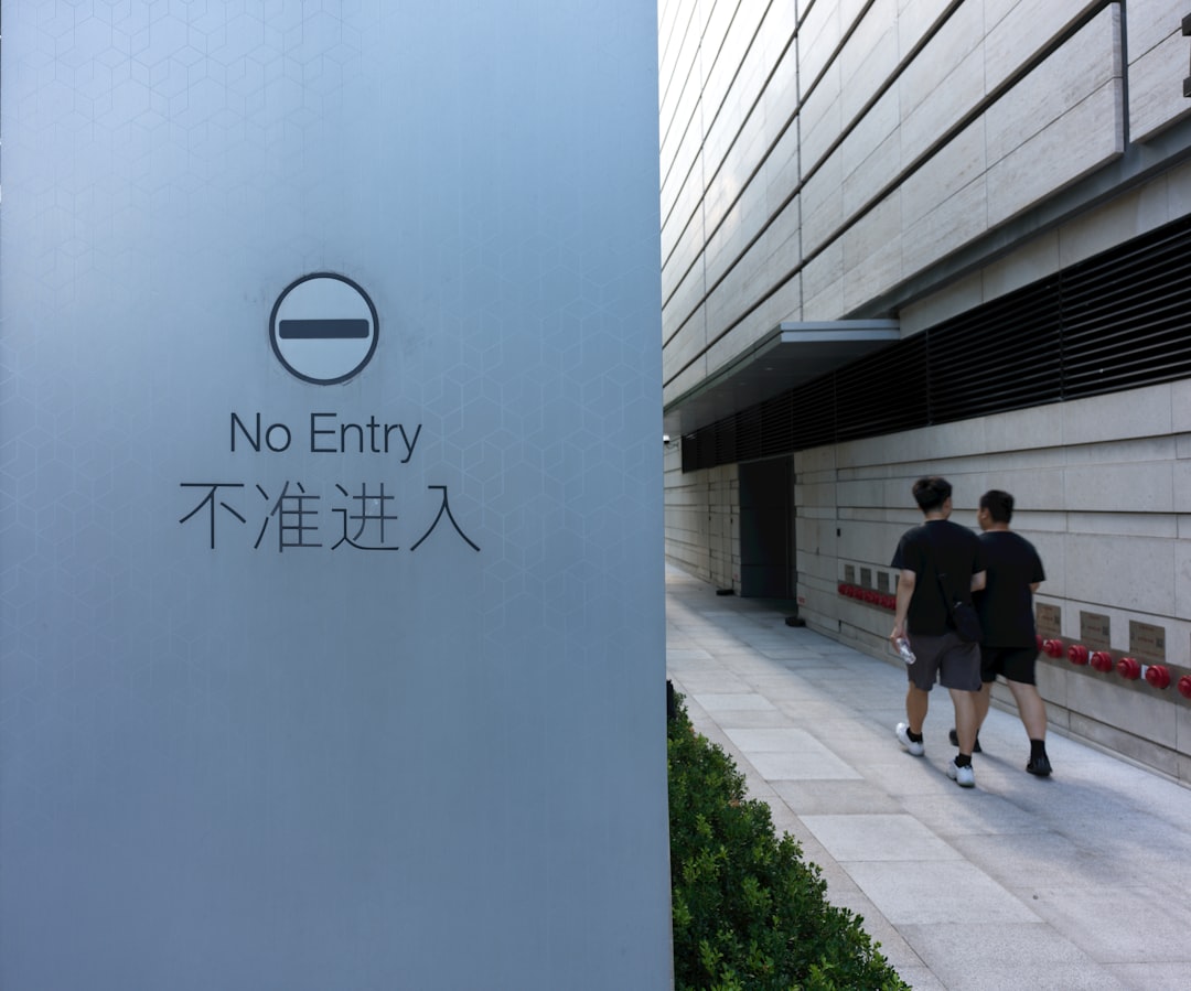 Two people walking down a sidewalk next to a building