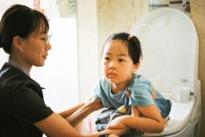 woman in black shirt carrying boy in blue polo shirt