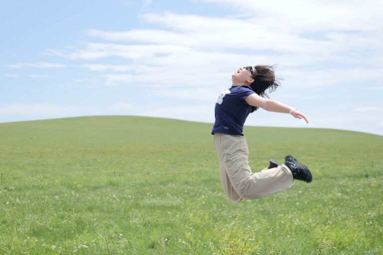 Person happily jumps in a grassy field.
